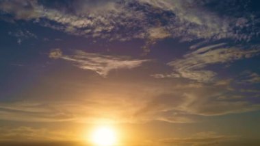 Güneş batıyor, bulutlar mavi ve turuncu dramatik gökyüzünde, güneş ışınlarıyla. Gece Gökyüzü zaman çizelgesi. Gün batımında hareket eden bulutlar. Akşam bulutları. Alacakaranlık gökyüzü zaman aşımına uğradı. Dramatik destansı akşam gökyüzü