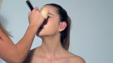 Makyajlı genç bayan. Yüzünüzü kapatın, makyaj yapın, rimel sürün. Makyaj sanatçısı cilt, kızartıcı ve pudra kullanıyor. Güzel kadın yüzü. Mükemmel ciltli güzel kız.