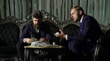 Amerikan para işi. Zengin beyefendi para sayar. Karanlık odada para sayan gangsterler. Zengin iş adamı. Zengin adam dolarları elinde tutar. 100 dolar içinde çok parası olan zengin bir adam.