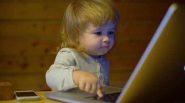 Bilgisayarlı bebek. Evde dizüstü bilgisayarla çalışan sarışın bir bebek. Akıllı küçük çocuk dizüstü bilgisayarını kullanıyor. Sevimli bebek bilgisayarı. Bilgisayardaki küçük kız. Bilgisayar kullanan bir çocuk