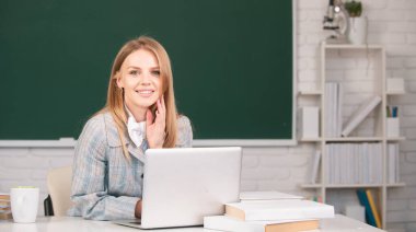 Lise öğrencisi sınıfta İngilizce ya da matematik öğreniyor. Dizüstü bilgisayar kullanan yaratıcı, gülümseyen kız öğrenci.