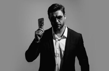 İyi ödeme. Yakışıklı adam gri stüdyoda izole edilmiş para tutuyor. Dolar banknotları halinde para. Yığınla para, finans, yatırım ve tasarruf. Model pankartı