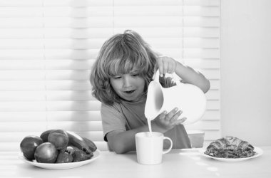 Kid pouring whole cows milk. Healthy food, vegetable dish