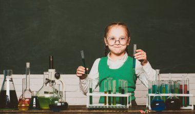 Ders Planları - Ortaokul Kimya. Okul dersindeki küçük çocuklar. Okul laboratuvarında kimya kazanan küçük çocuk bilim adamı. İlkokuldan gelen çocuk