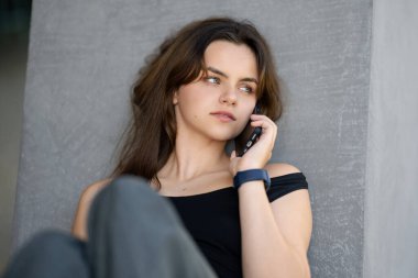 Ergen kız telefonda konuşuyor. Açık havada cep telefonu kullanan bir kız. Genç kız cep telefonuyla konuşuyor. Genç kız akıllı telefondan arıyor. Ergen telefonda konuşuyor. Romantik bir ruh hali. İlk aşk