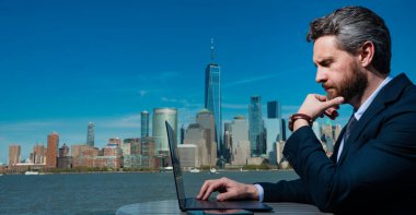 New York 'ta dışarıda dizüstü bilgisayar kullanan olgun bir iş adamının fotoğrafı. İş dünyası Amerikan başarısı. Uzaktan bağımsız çalışma. ABD 'de online iş. İş başarısı. Yönetim stratejisi. Dışarıdaki iş
