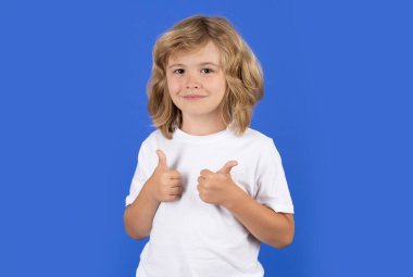 Stüdyoda izole edilmiş arka planda onay veren bir çocuk. Çocuk portresi baş parmak işareti yapıyor. Sevimli gülümseyen çocuk, izole edilmiş stüdyo geçmişi.