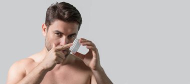 Erkek cilt bakımı için kozmetik kremi reklamı yapan bir adam. Erkek derisi için krem. Erkek derisi. İzole edilmiş stüdyo afişi. Erkekler için organik kozmetik. Doğal insan cilt bakımı için kozmetik tutuyor.