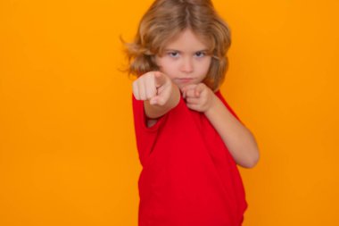 Kırmızı tişörtlü çocuk sarı izole edilmiş stüdyo geçmişini gösteriyor. İşaret parmağı olan çocuk seni işaret ediyor