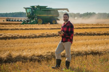 Hasat zamanı. Tarlada çalışan bir adam. Kırsal kesimde geleneksel tarım. Hasat tarlaları olan çiftlik arazisi. Olgun arpa toplayan çiftçi. Çiftçi hasatı kontrol ediyor. Denetleyen adam