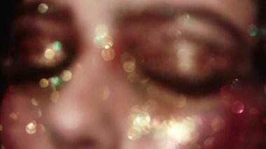 Güzellik suratında parıltı. Modellerin yüzüne parlak bir makyaj. Yaratıcı neon parıltılı yüz sanatı. Parıldayan kozmetik ürünleri olan seksi bir kadın. Renkli sim makyajı. Sinematik güzellik modeli metalik parlaklık. Sanat kadını yüzü