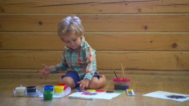 Anaokulu çocukları. Küçük şirin bir çocuk resmi ve çizimi. Pastel boyalı ve kağıda çizim yapan bir çocuk. Çocuklar için yaratıcı bir oyun. Suluboya kullanarak rengarenk boyalı bebek resmi.