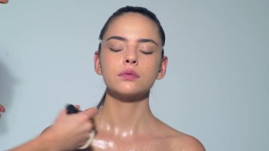 Profesyonel makyöz güzel genç bir kadınla çalışıyor. Genç manken için makyajı kapat. Makyaj sanatçısı makyaj yapıyor. Profesyonel makyöz, cazibe modeli makyajı yapıyor.