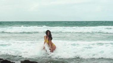 Okyanus dalgalarının kıyısında bikini mayo giymiş genç bir kadın. Tatil, seyahat, rahatlama konsepti. Seksi kadın okyanus suyu, özgürlük ve hayat güzel bir kumsal. Deniz sahilinde tatiller