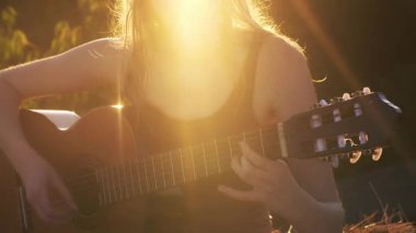 Gün batımında gitar çalan kız. Gitarlı romantik bir kadın. Açık havada güzel bir şarkıcı. Yetenekli gitarist. Şehvetli bir müzisyen. Gitarlı şehvetli bir kadın. Müzik çalan sanatçı kadın. Kadın.