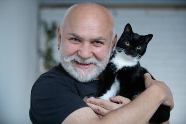 Yaşlı bir adamın kedisine sarılışının portresi. Büyükbaba evcil hayvanıyla sakin bir anın tadını çıkarıyor. Emekli adam ve kedisi evde. Yaşlı adam kedisine sevgiyle bakıyor. Son sınıf öğrencisi ve kedileri evde.