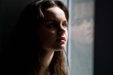 Hayalperest kızın yakın portresi. Pencerenin yanında hayal ediyorum. Küçük hayalperest. Hayalperest genç yukarı bakıyor. Gençlik suratı. Rüya gibi bir ifadesi olan ergen bir kız. Düşünceli bir kızın yakın çekimi.