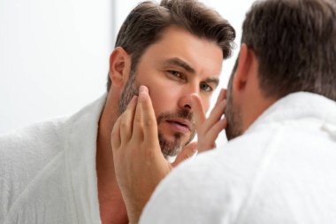 Güzellik uzmanı sağlıklı cilt için nemlendirici yüz kremi, erkek derisi konsepti kullanır. Erkek güzellik ve cilt bakımı portresi. Tıraş olduktan sonra sağlıklı bir yüz, yüz bakımı, cilt bakımı.