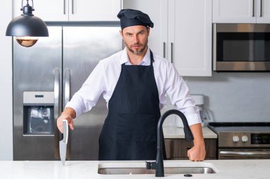 Yemek pişirme ve aşçılık konsepti. Mutfakta üniformalı aşçı. Erkek aşçı ya da önlüklü aşçı. Aşçının bereli portresi. Yemek pişirme konsepti