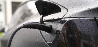 Elektrikli araba şarj oluyor. Benzin istasyonu şarj ediliyor. Yeşil enerjili şarj istasyonu, halka açık otoparkta EV arabalı elektrikli araç. Şarj edilecek güç istasyonu