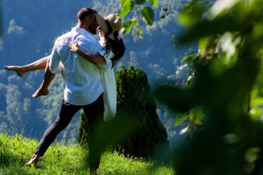 Seksi çift, doğanın güzelliğinin ortasında tutkuyla kucaklaştı. Romantik bir öpücük. Doğayı öpen çiftler. Öpüşen çiftler. Yaz doğasına aşık romantik çift. Tutkulu bir öpücük