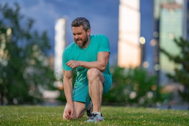 Acı üstüne acı. Diz ağrısı çeken atletik bir adam. Bacağını tutan yaralı bir adam. Koştuktan sonra acı. Dizinden yaralanan bir adam. Antrenman bacak ağrısı. Koşu diz travmasına yol açıyor.