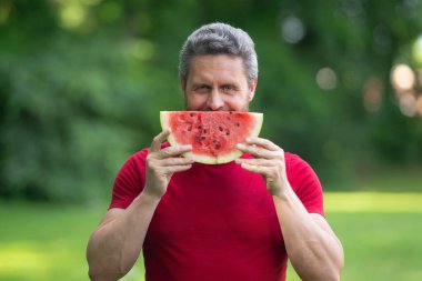 Karpuzlu bir adamın yaz portresi. Yaz parkında karpuz yiyen komik adam. Bahçede karpuz yiyen İspanyol bir adam. Adam dışarıda meyve yiyor. Yaz erkek portresi, karpuz