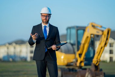 İnşaat alanında mimar. İnşaat alanında kask ve takım elbiseli mimar. İnşaatta duran kendine güvenen bir mimar. Yatırımcı ya da inşaat mühendisi. İspanyol 'un açık hava portresi
