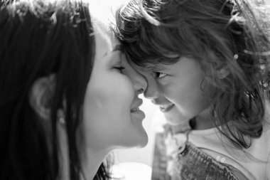 Sevgi dolu bir anneyle mutlu çocukluk anıları. Anne ve kızı arasındaki şefkatli sevgi. Sevgi dolu bir ailenin güzel açık hava portresi. Gülümseyen anne ve kız hassas bir anın tadını çıkarıyorlar.