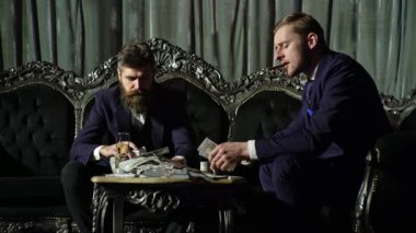 İki zengin adam. Karanlık odada para sayan gangsterler. Zengin iş adamı. Zengin adam dolarları elinde tutar. Dolar olarak çok parası olan zengin bir adam.