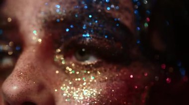 Güzellik suratında parıltı. Modellerin yüzüne parlak bir makyaj. Yaratıcı neon parıltılı yüz sanatı. Parıldayan kozmetik ürünleri olan seksi bir kadın. Renkli sim makyajı. Sinematik güzellik modeli metalik parlaklık. Sanat kadını yüzü