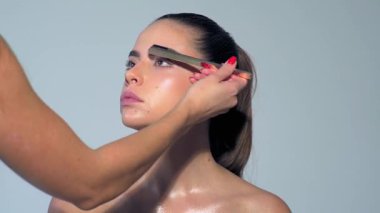 Profesyonel makyöz güzel genç bir kadınla çalışıyor. Seksi mankeni telafi et. Makyaj sanatçısı güzel makyaj yapıyor. Profesyonel makyöz, cazibe modeli makyajı yapıyor.