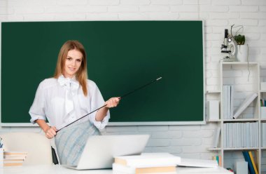 İşaretçi ile genç öğretmen. Okul sınıfında okuyan genç, kendinden emin ve çekici bir kız öğrencinin portresi.