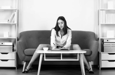 Seksi bacaklı baştan çıkarıcı sekreter ofiste kanepede oturur. Seksi bir iş kadını. Şehvetli kız çalışan.