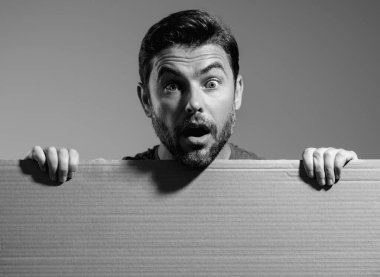 Şaşkın adamın elinde beyaz kart var, boş kart. Ürününüz için pankart hazır. Mesajını imzala. Stüdyonun arka planında boş tabela göstermesi hayret verici. Boş tahta var. Reklam alanı