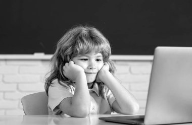 Laptop kullanan neşeli bir çocuğun portresi. Çevrimiçi öğrenme teknolojisi