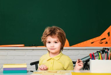 Mutlu, sevimli, çalışkan çocuk kapalı bir masada oturuyor. Bireysel eğitim