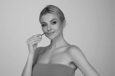 Studio portrait of beautiful woman with red lipstick. Beautiful young woman applying lipstick on her lips, isolated on studio background