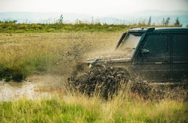 Dağ yolunda SUV 'un önü alçak açılı. Kötü çakıllı yolda arazi aracı. Çamur ve su off-road yarışında sıçrıyor