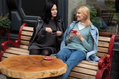 Kadınlar dışarıda kahve içer. Birlikte kahve içen kadınlar. Havalı sarışın ve esmer kadınlar dışarıda sohbet ederken kahve fincanları tutarlar. Tatlı bir kafede kahve içip rahatlayan kızlar.