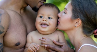 Karışık aile portresi. Dışarıda çok ırklı mutlu bir aile var. Küçük melez çocuğu olan uluslararası aile annesi ve babası. Afrikalı Amerikalı babanın ailesi kucağında küçük bir bebek taşıyor. Mutlu ebeveynler