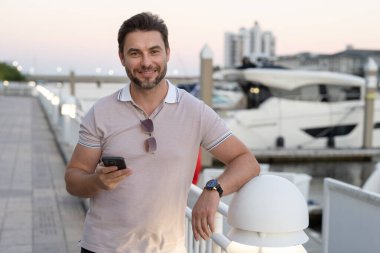 Şehirde telefonla konuşan yakışıklı, kendine güvenen bir adamın portresi. American City 'de telefonla konuşan adam. Polo giymiş seksi bir adam. Moda erkeği Tampa 'da sokakta poz veriyor. Bisiness telefon görüşmesi