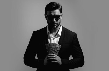 Gri arka planda nakit para tutan bir portre işçisi. Büyük şans, afiş. Dolar nakit para konsepti. Nakit kazanınca seviniyor. Nakit parası olan bir adam. Finansal şans ve başarı