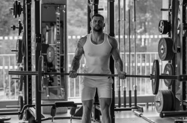 Muscular man lifting weights at gym. Handsome guy prepare to do exercises with dumbbell