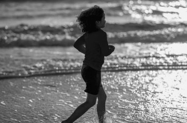 Heyecanlı çocuk yaz denizinde su sıçratarak oynuyor. Yaz tatili. Çocuk denizde dalgalarla oynuyor. Küçük çocuk denizde oynuyor ve su damlaları sıçrıyor. Çocuk denizde su sıçratmaca oynuyor. Yaz tatili