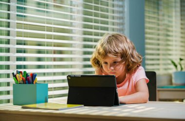 Elinde tablet olan küçük bir anaokulu öğrencisi. Ev okulu çocukları.