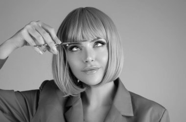 Beauty young woman cutting hair with scissors isolated on studio background. Beautiful girl about to cut hair. Hair cut scissors concept. Hairdresser scissors change hairstyle. Hair model hold
