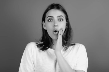 Young surprised woman in t-shirt shouting wow, studio background. Shock content. Surprised woman raised eyebrows with surprised face. Young woman shocked with surprise and amazed expression clipart