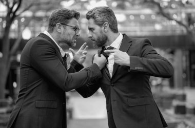 İki dövüşçü iş adamı yumruk atıyor. İş adamları dışarıda kavga ediyor. İş adamlarının iş anlaşmazlıkları var. İş adamları sert dövüşüyor ve dışarıda yumrukluyor. Anlaşmazlık