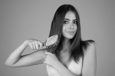 Girl combing hair with comb. Beautiful young woman holding hair comb. Female model hold comb near face. Woman portrait with comb